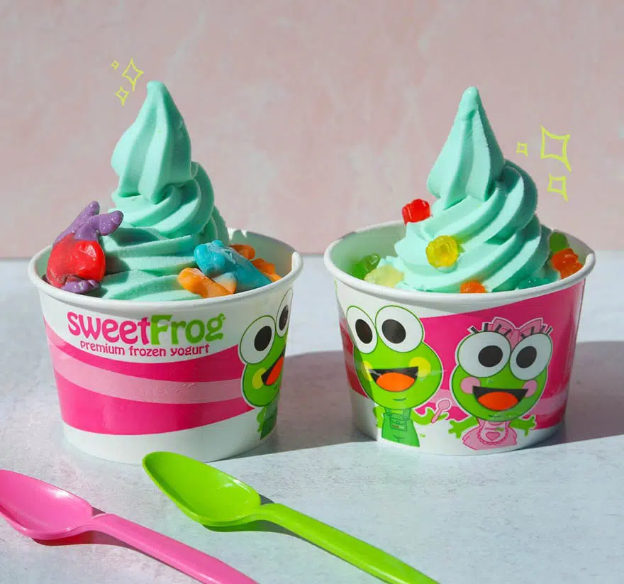 Two Cups Of Frozen Yogurt With Gummy Bears And Spoons On A Table